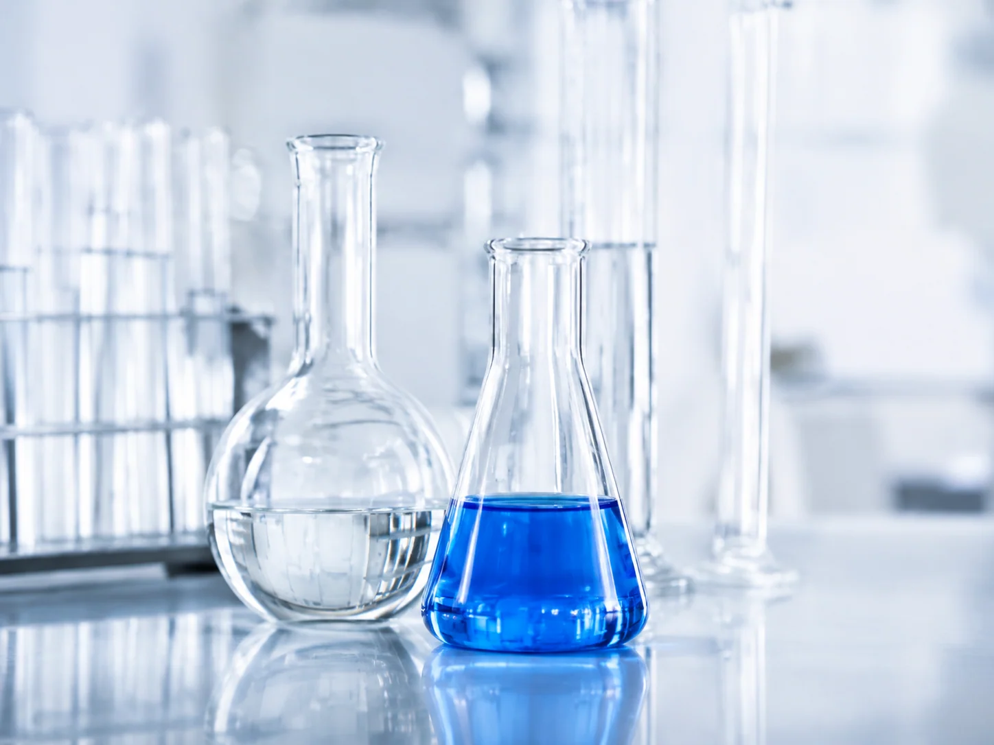 Clear laboratory glassware containing blue formulation liquids