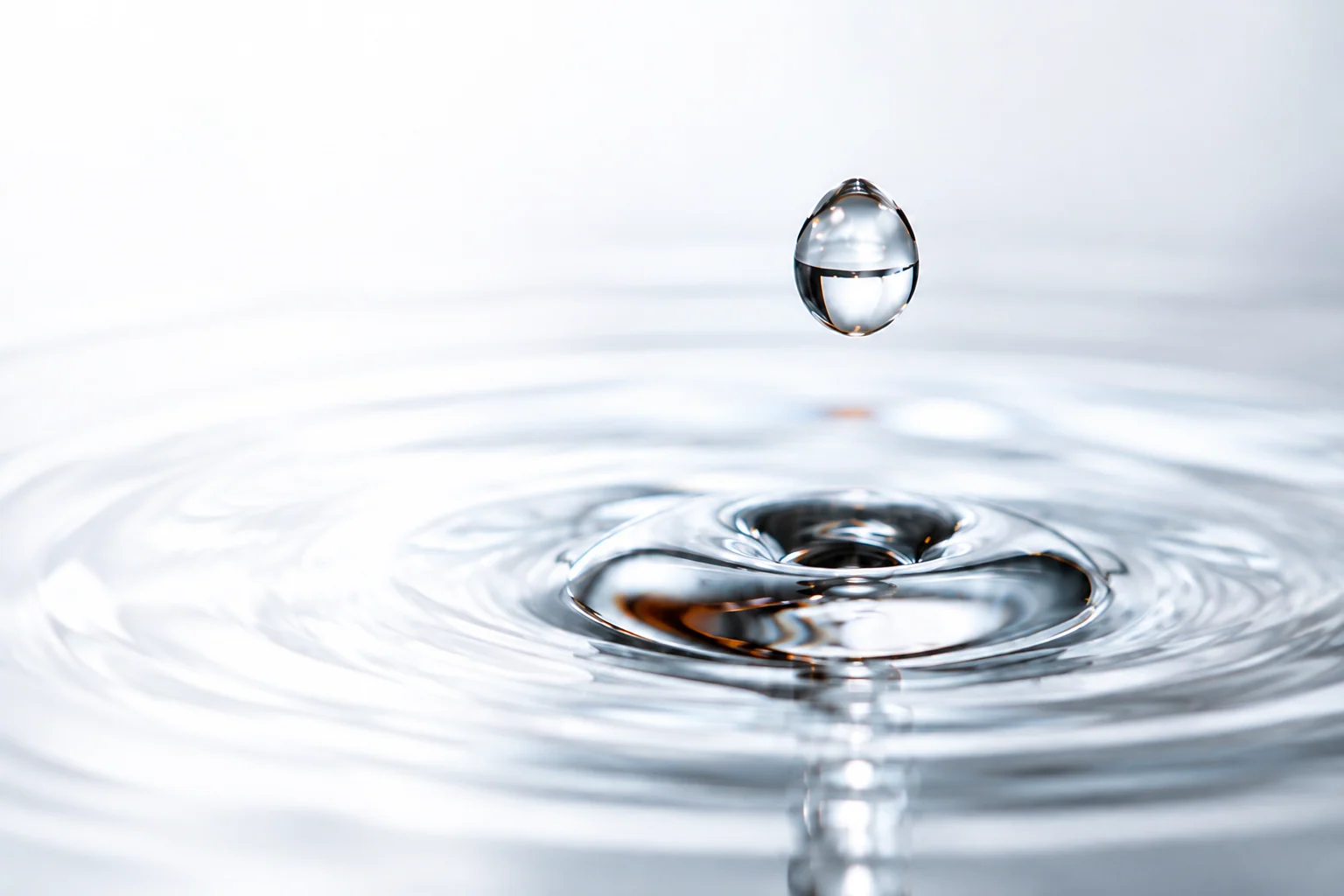 A clear resin droplet above a smooth reflective liquid surface